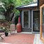 A private back patio with rain barrel for water collection, and french doors that open to a bedroom.