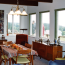 A dining room with mid-century furniture and large windows looking out over the front deck and to the ocean.