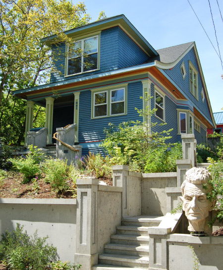 Splendid view of rental home with a light blue siding and shaded by a tree.